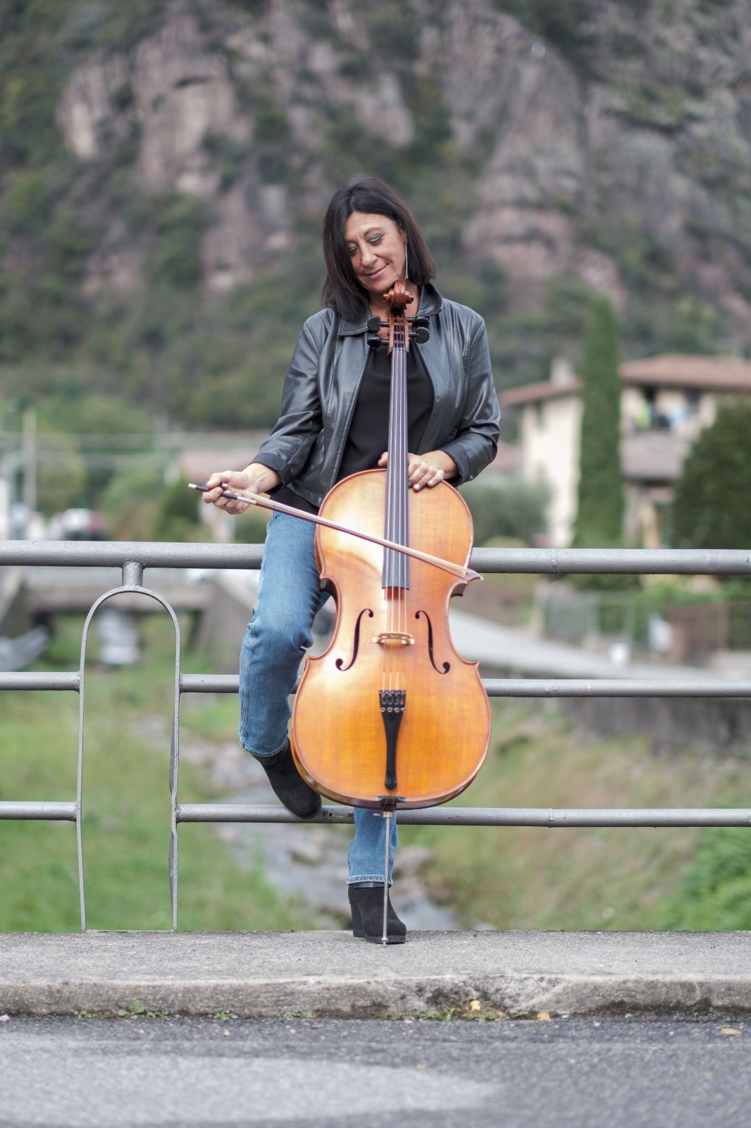 Ilaria Giorgi, violoncellista per eventi, con il violoncello su un ponte tra le montagne